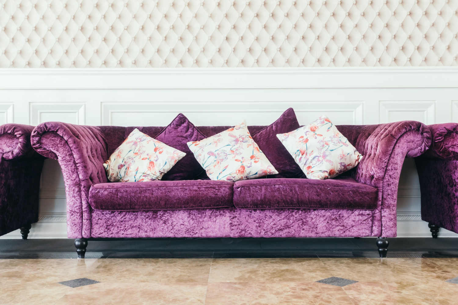 Plush purple sofa with floral cushions
